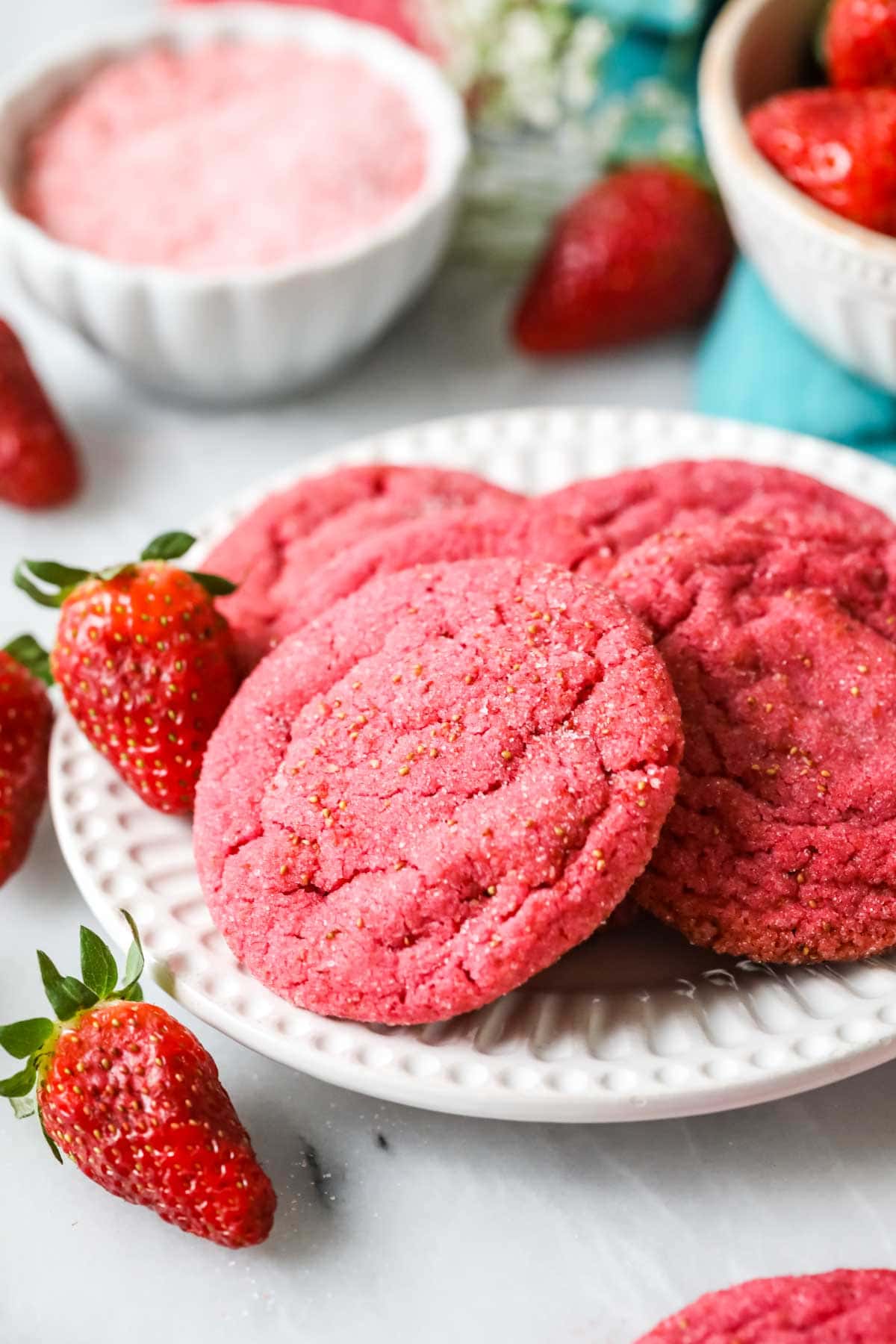 Pinkfarbene Kekse aus gefriergetrockneten Erdbeeren auf einem weißen Teller.