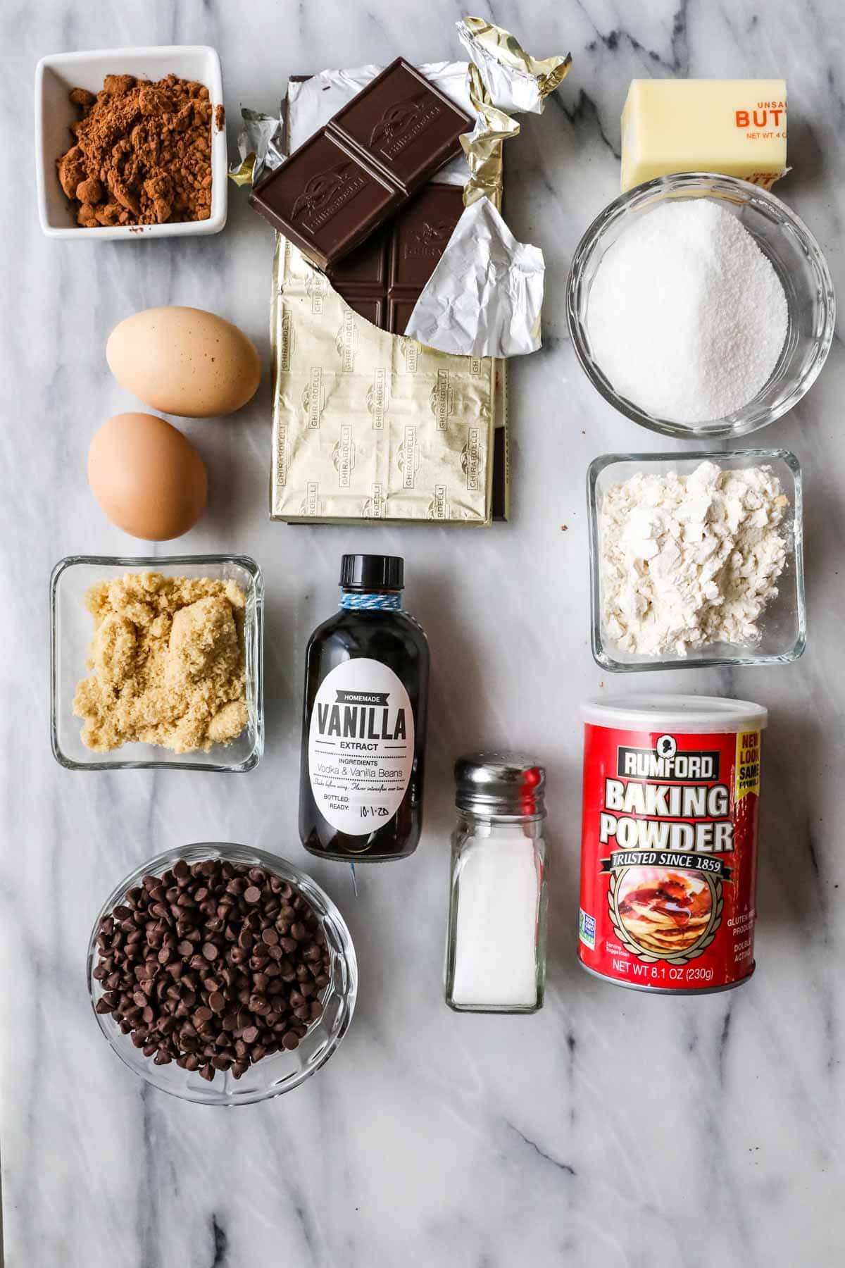 Overhead view of ingredients including cocoa powder, chocolate, brown sugar, eggs, and more.