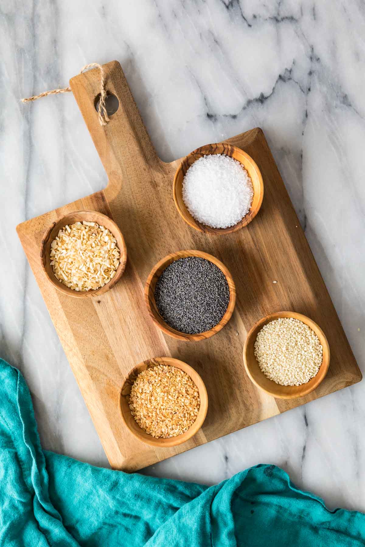 Overhead view of ingredients in bowls including salt, sesame seeds, poppy seeds, and more.