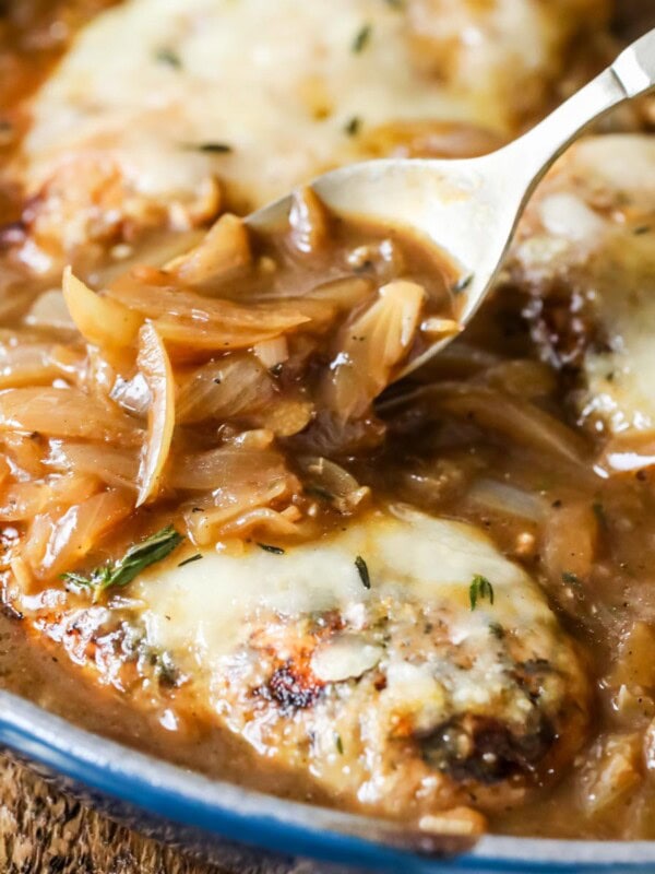 Caramelized onion gravy being spooned over french onion chicken.