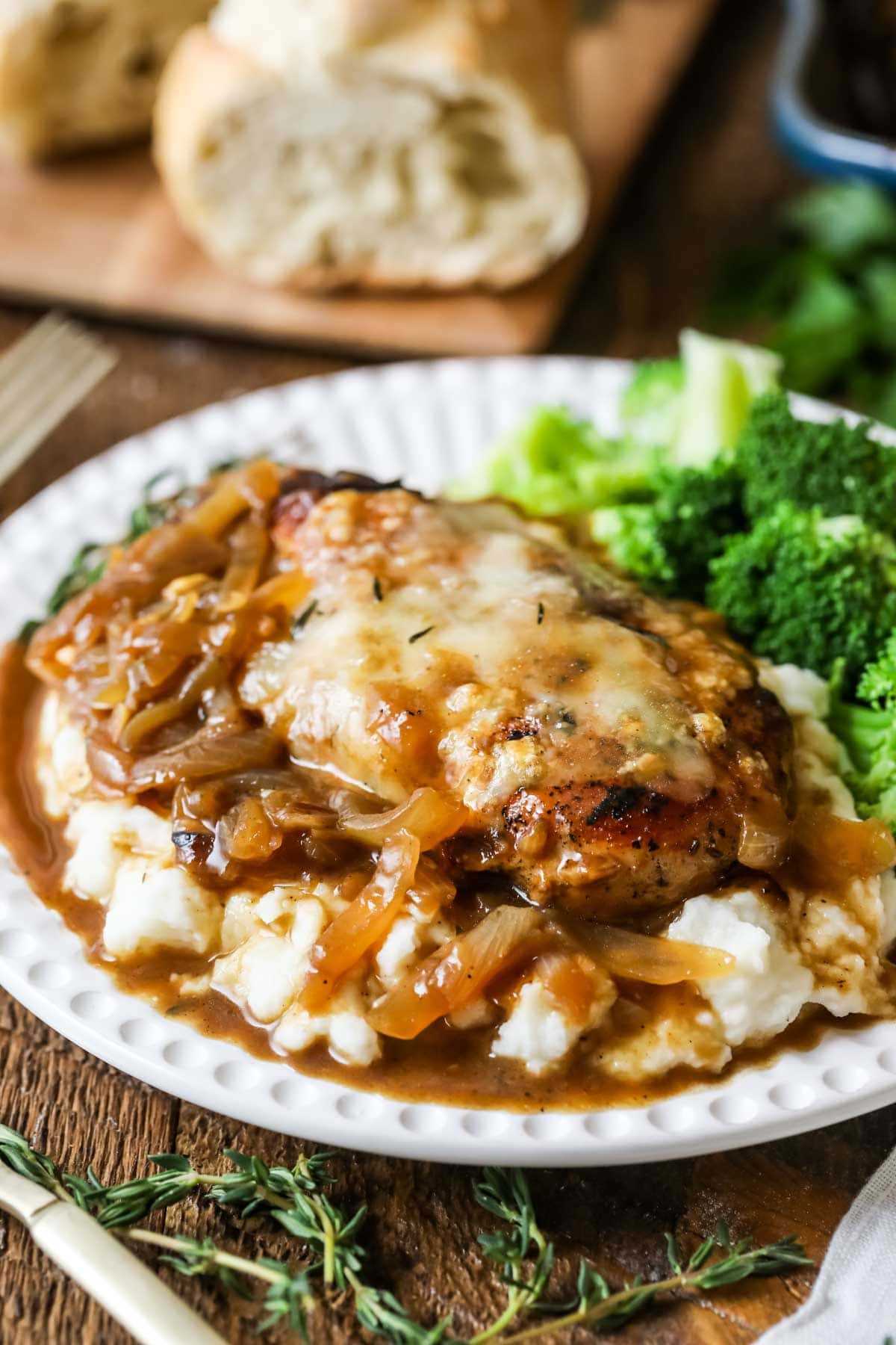 Plate with french onion chicken served over mashed potatoes with steamed broccoli on the side.