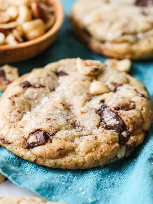 Hazelnut cookies with chocolate chips and sea salt resting on a teal tea towel.