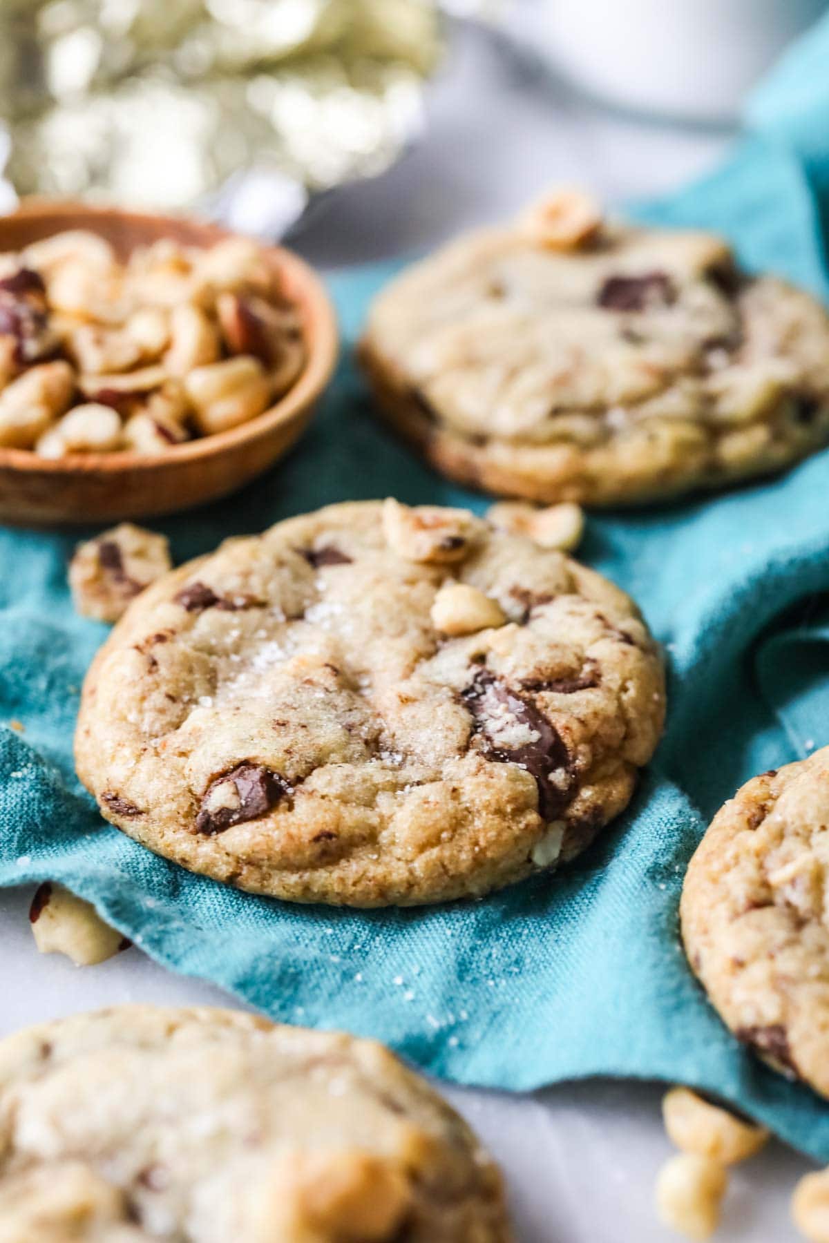 Hazelnut cookies with chocolate chips and sea salt resting on a teal tea towel.