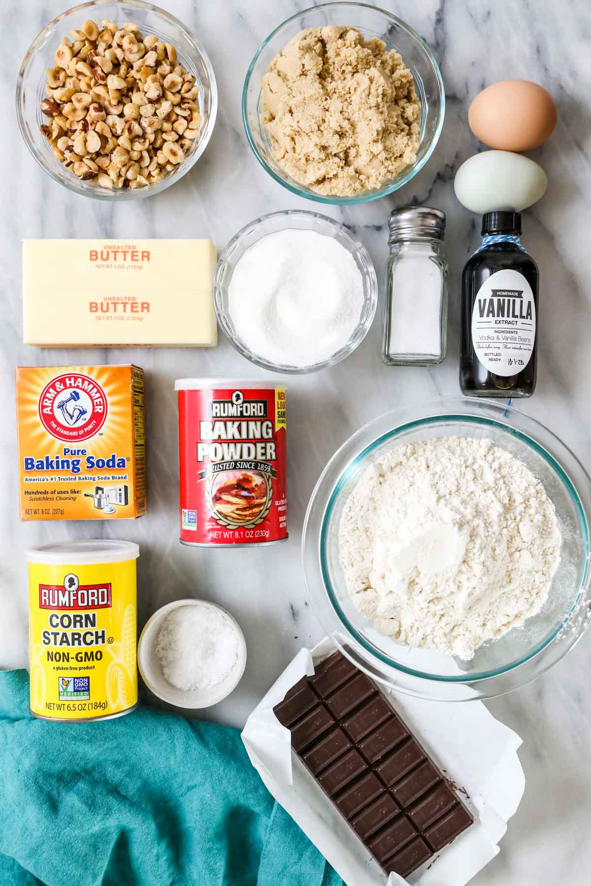 Overhead view of ingredients including hazelnuts, butter, flour, chocolate, and more.
