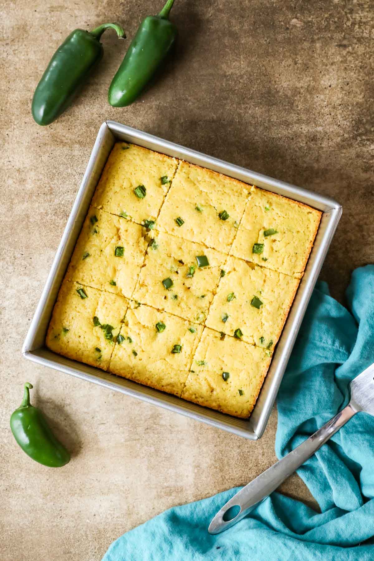 Overhead view of a square metal pan of cornbread made with jalapeno.