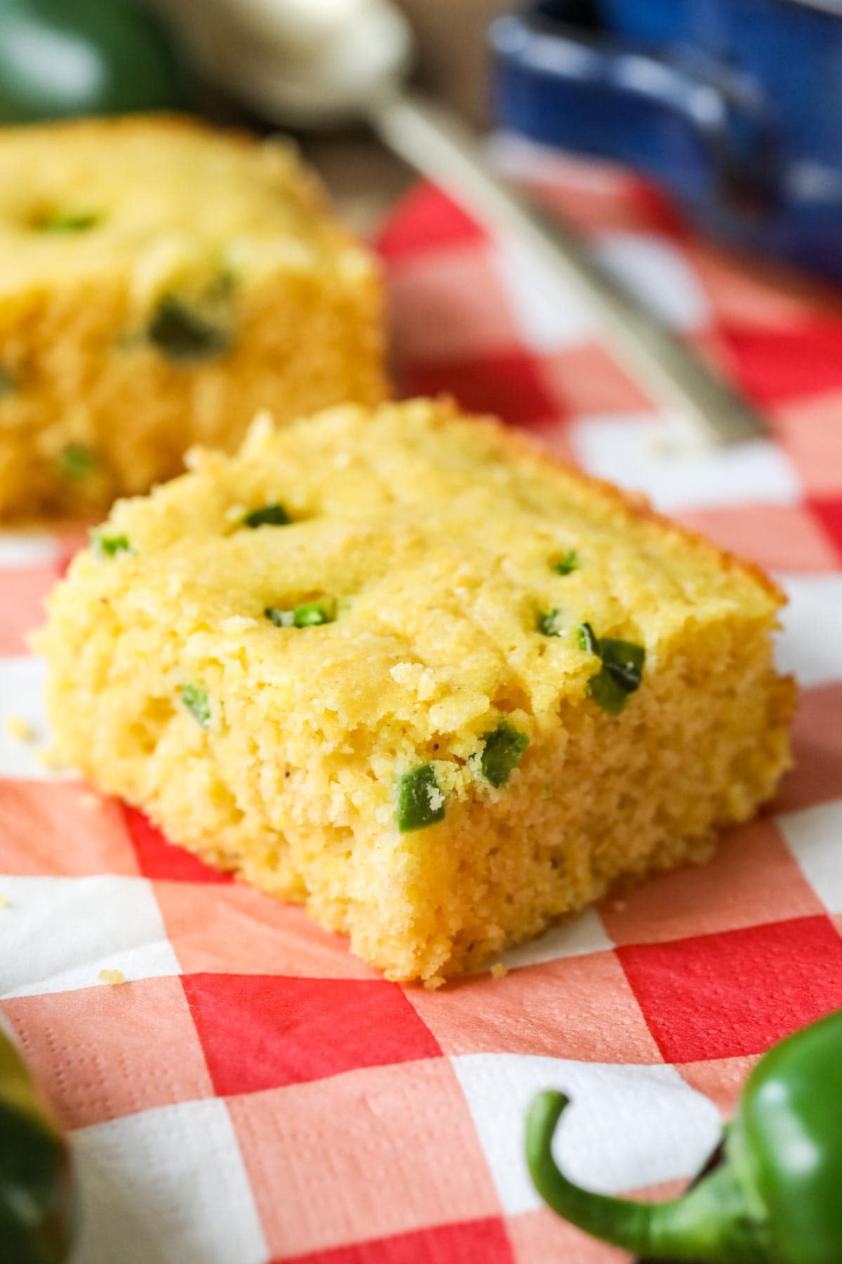 Square slice of jalapeno cornbread on a red checked tablecloth.