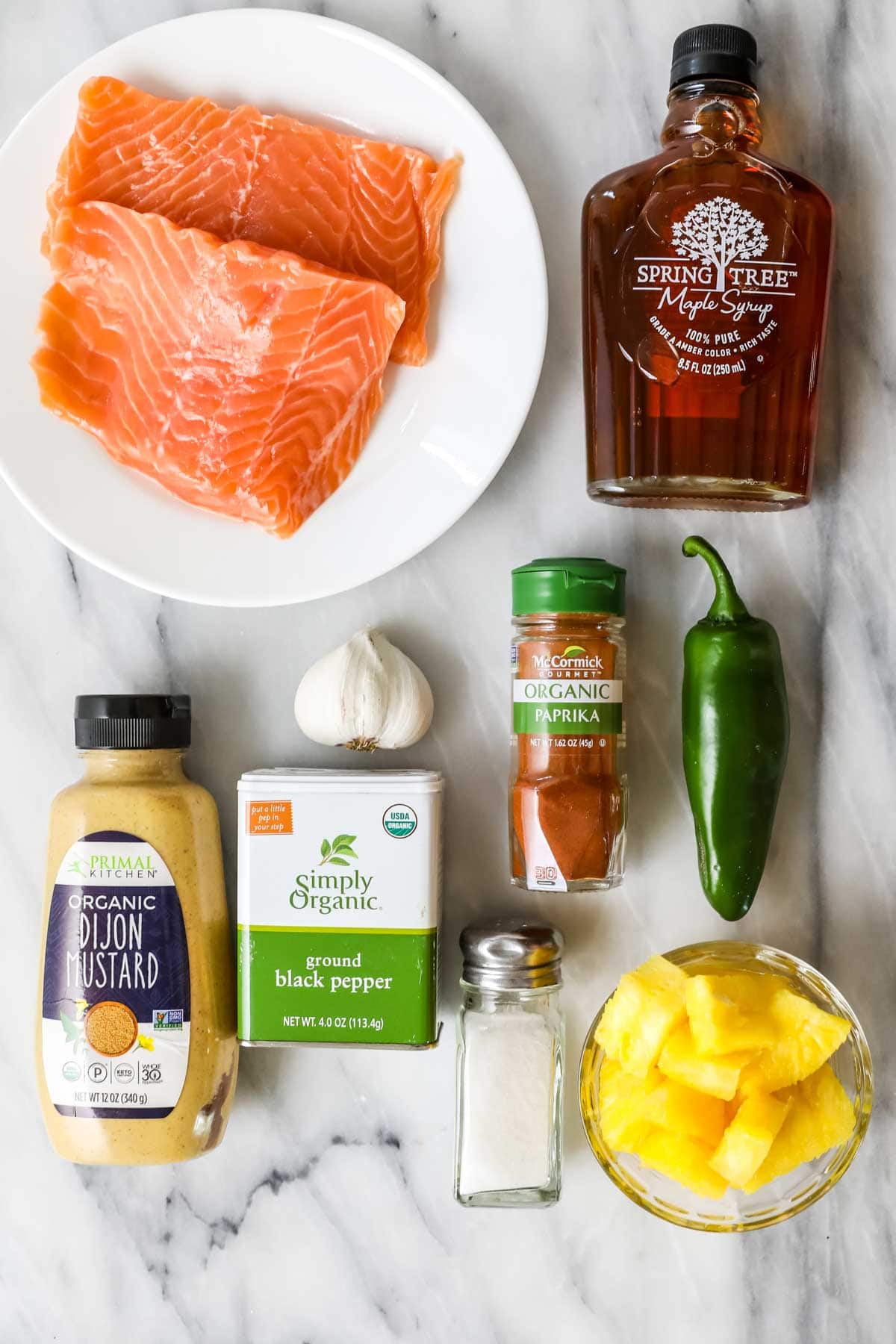 Overhead view of ingredients including salmon, maple syrup, pineapple, jalapeno, and more.