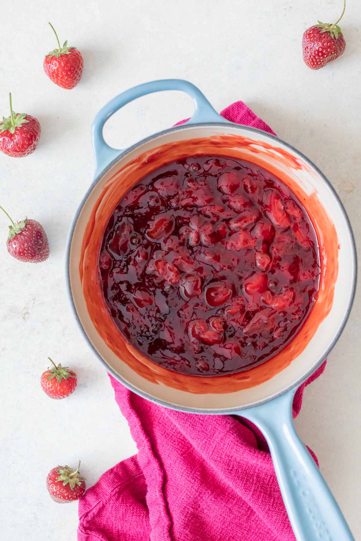 Overhead view of a saucepan with strawberries that have been broken down into a sauce.