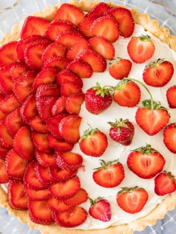 Overhead view of a strawberry tart with half of the tart covered in strawberry slices and the other half with strawberry halves.