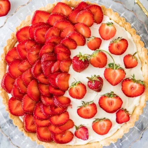 Overhead view of a strawberry tart with half of the tart covered in strawberry slices and the other half with strawberry halves.