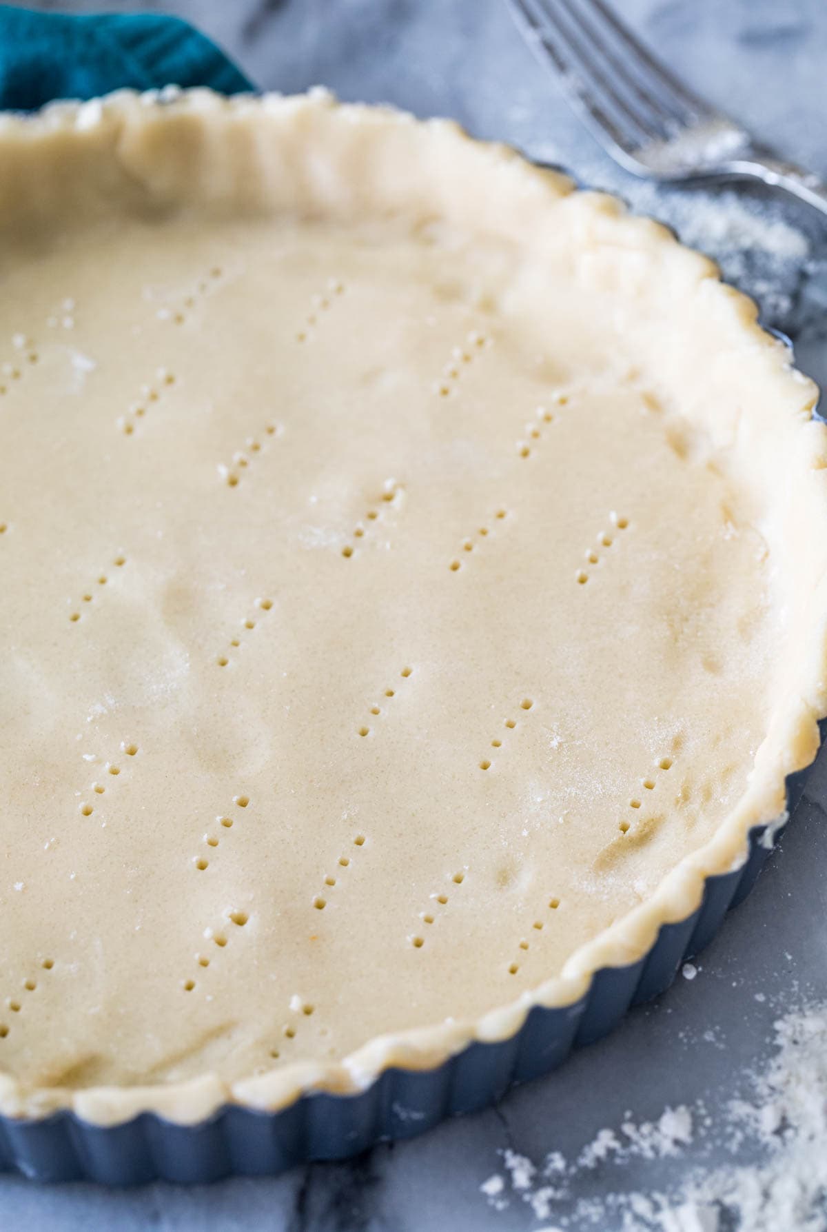 Close-up view of an unbaked tart crust that's been pricked with a fork.