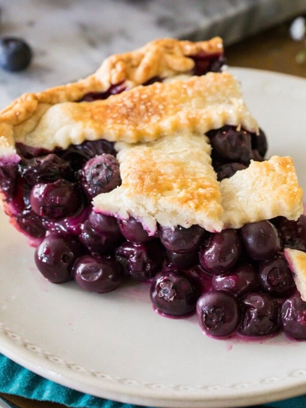 Slice of blueberry pie with a lattice crust on a white plate.