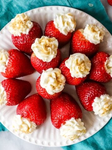Overhead view of cheesecake stuffed strawberries arranged in a circle on a plate.