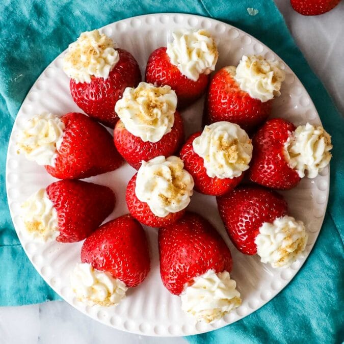 Overhead view of cheesecake stuffed strawberries arranged in a circle on a plate.