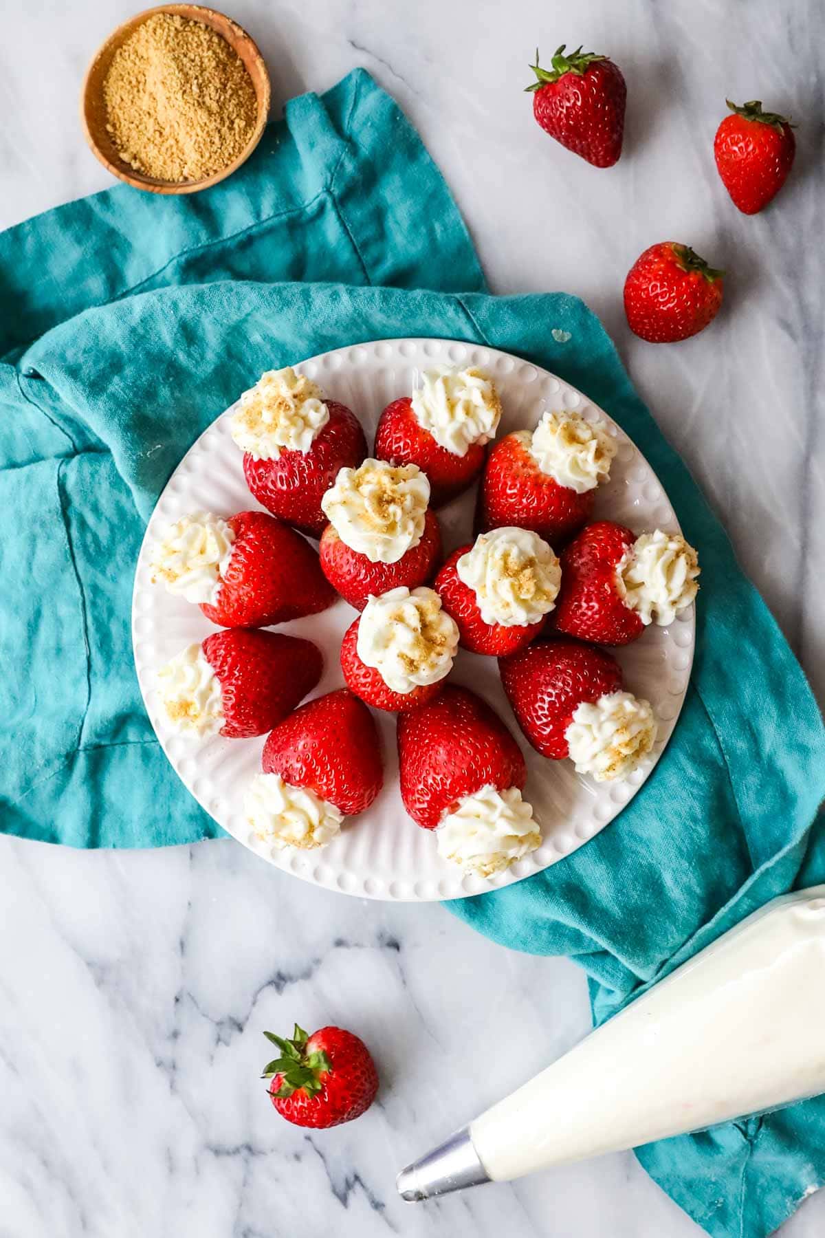 Overhead view of cheesecake stuffed strawberries arranged in a circle on a plate.