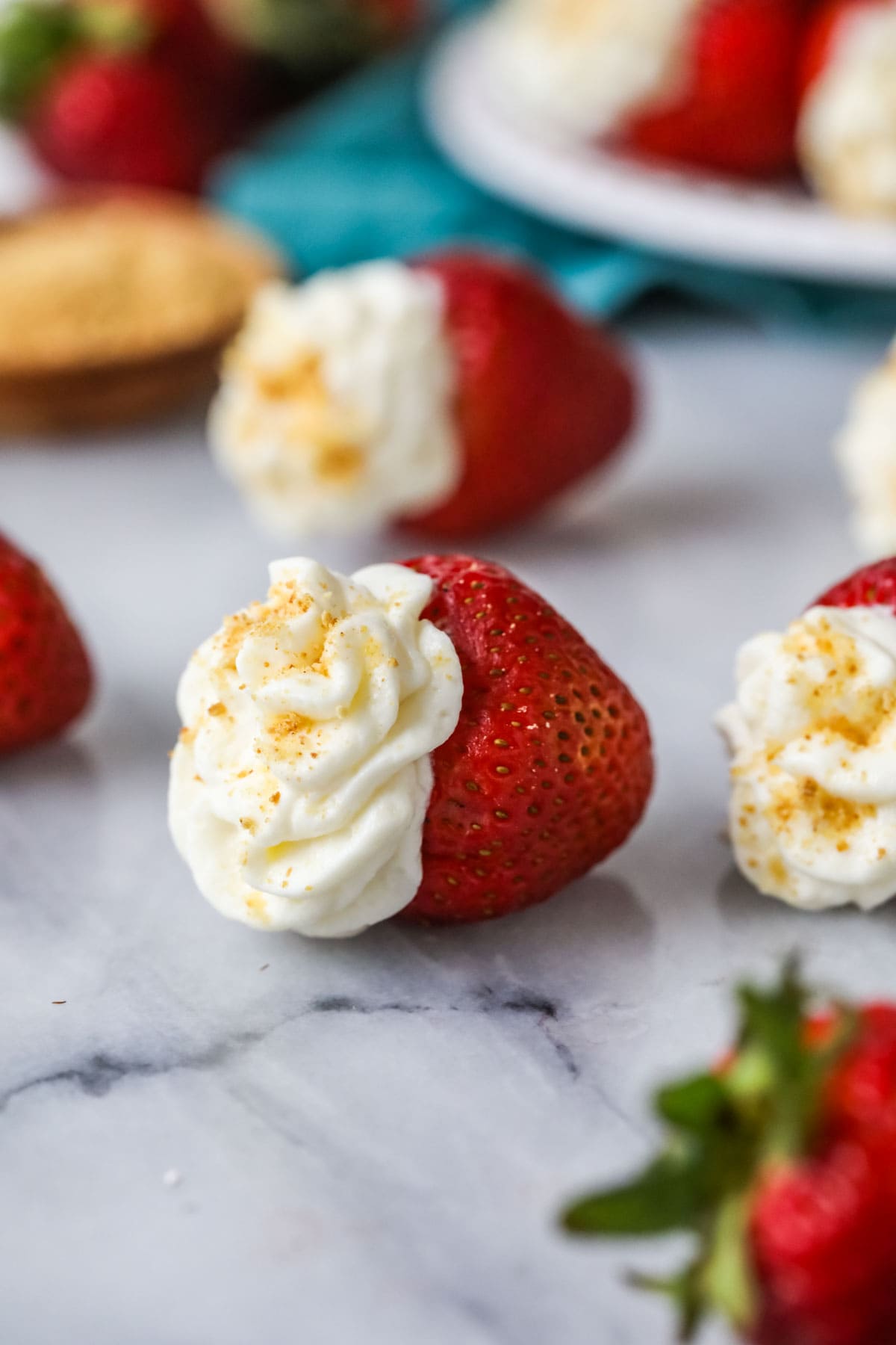 Strawberry that has been filled with a cheesecake mixture and topped with graham cracker crumbs.