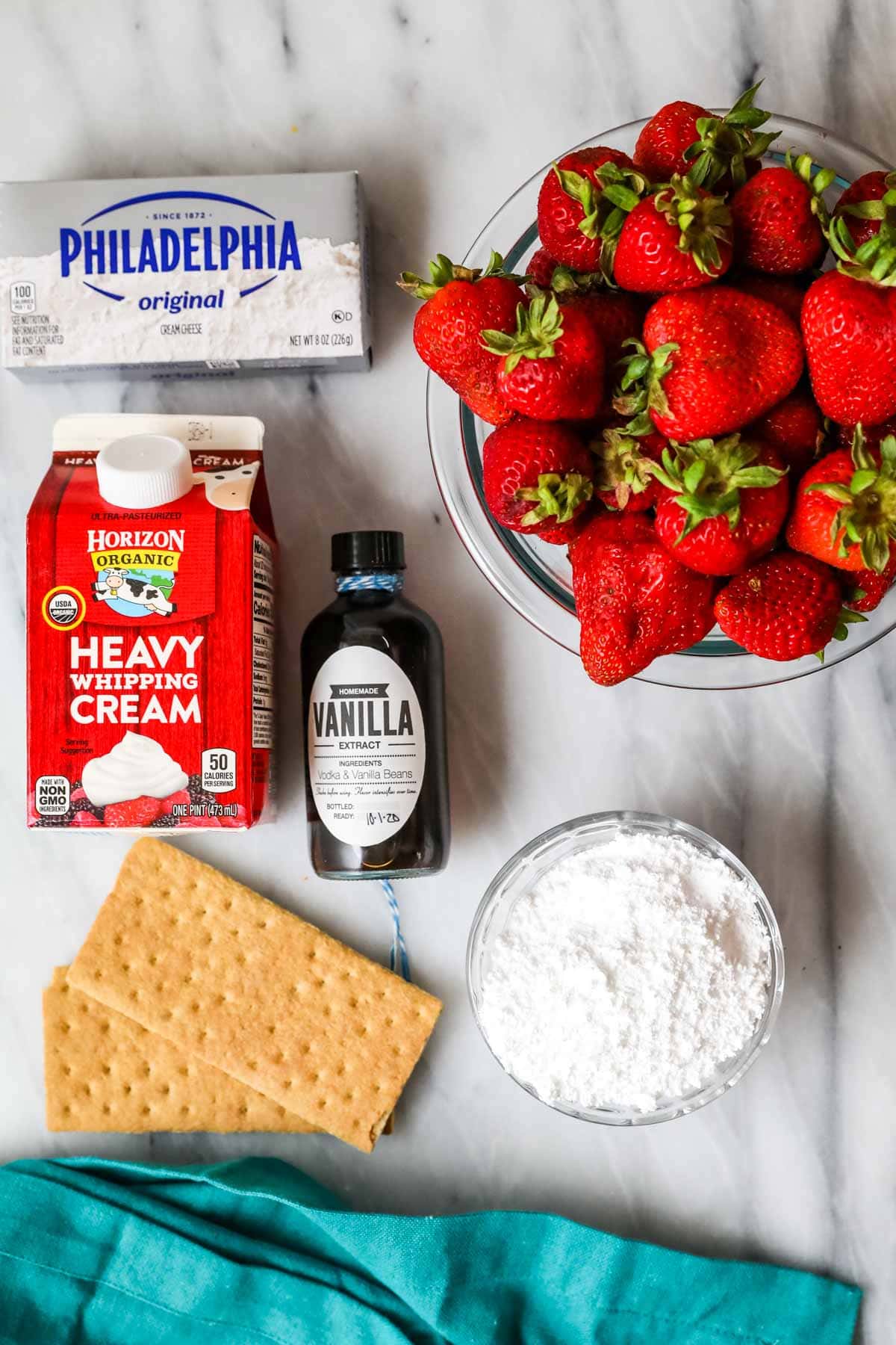 Overhead view of ingredients including strawberries, graham crackers, cream cheese, and more.