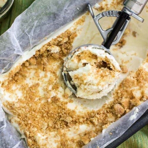 Overhead view of an ice cream scoop resting in a container of homemade key lime pie ice cream.