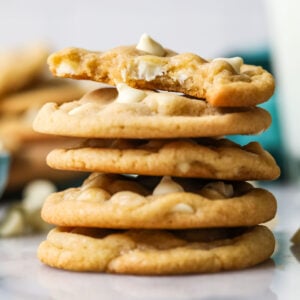 Stack of white chocolate chip cookies with the top cookie missing a bite.