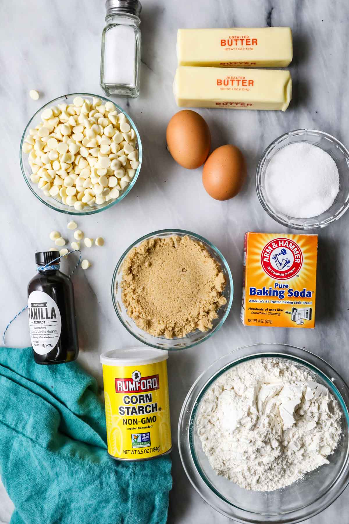 Overhead view of ingredients including eggs, white chocolate chips, brown sugar, and more.