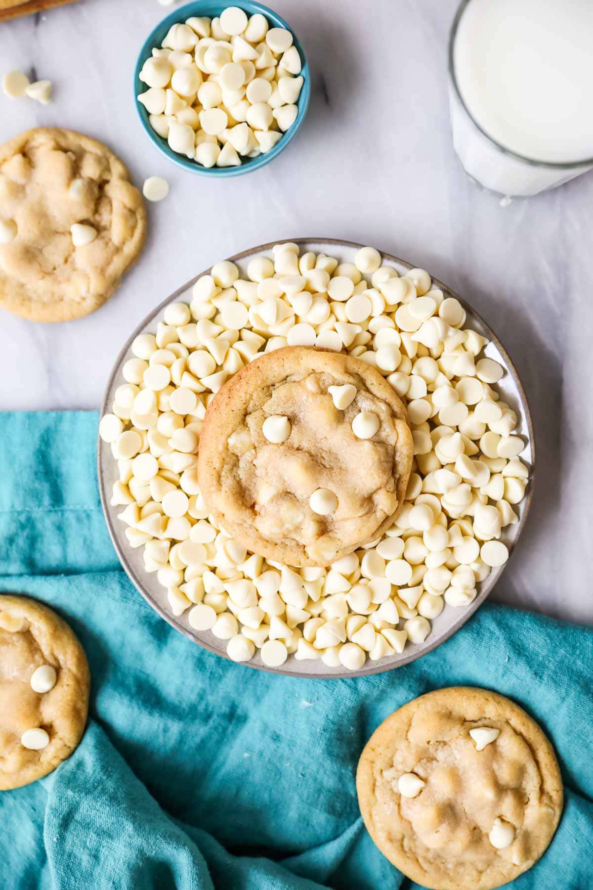 Overhead view of a white chocolate chip cookie sitting in a bowl of white chocolate chips.