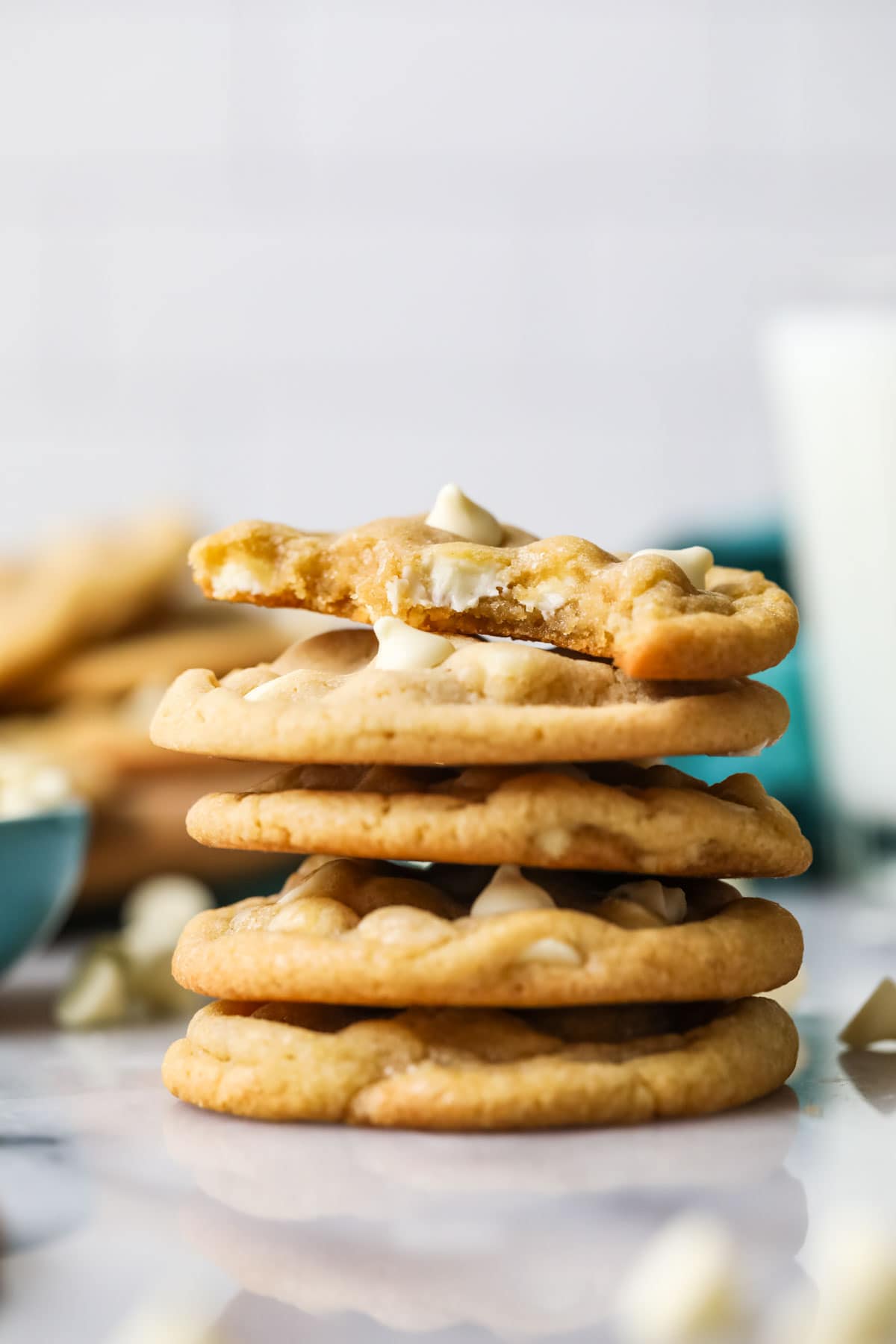 Stack of white chocolate chip cookies with the top cookie missing a bite.