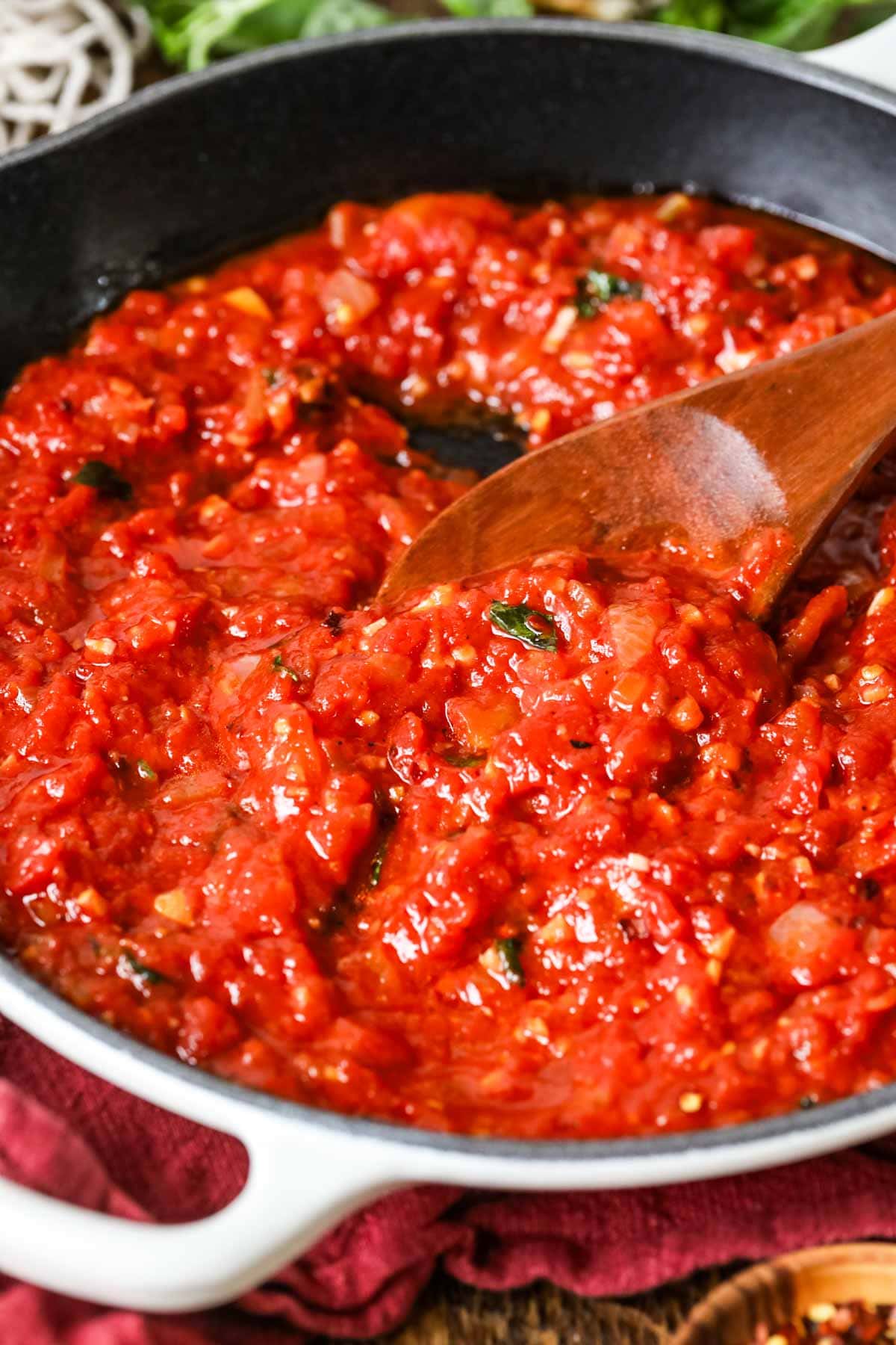Pot of arrabiata sauce being stirred with a wood spoon.