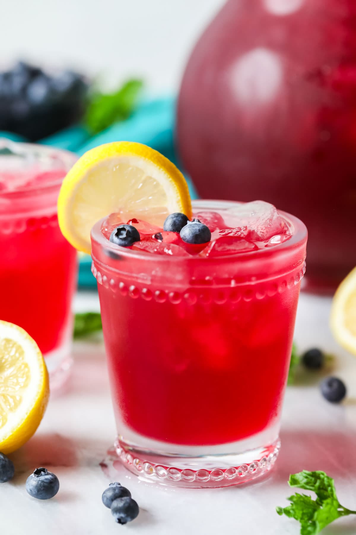 Glass of blueberry lemonade garnished with blueberries and a lemon slice.