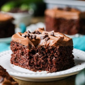 Square slice of frosted chocolate zucchini cake missing a bite.