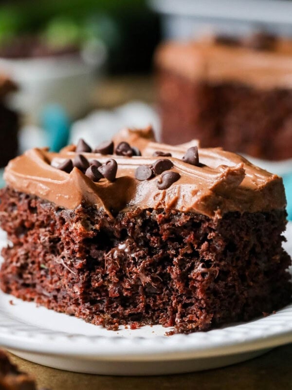 Square slice of frosted chocolate zucchini cake missing a bite.