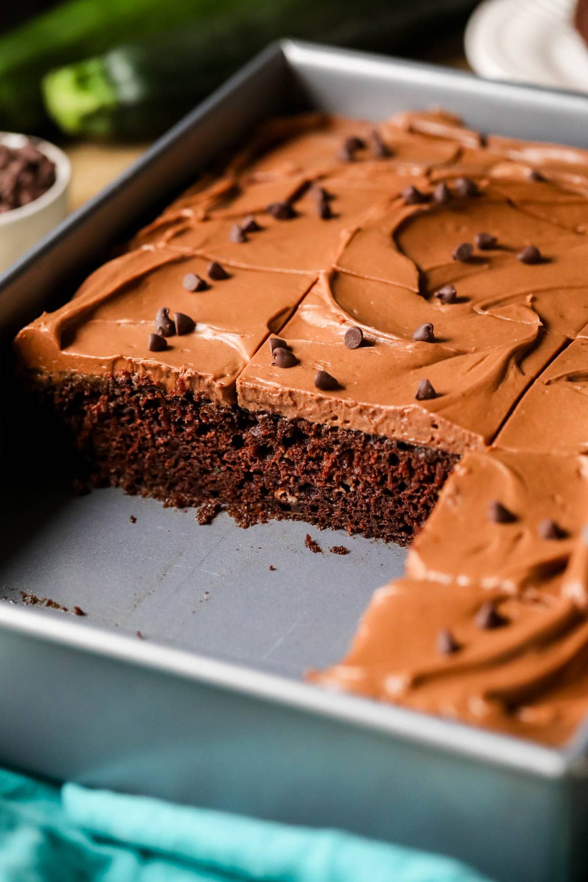 Metal pan of chocolate zucchini cake missing a few slices.