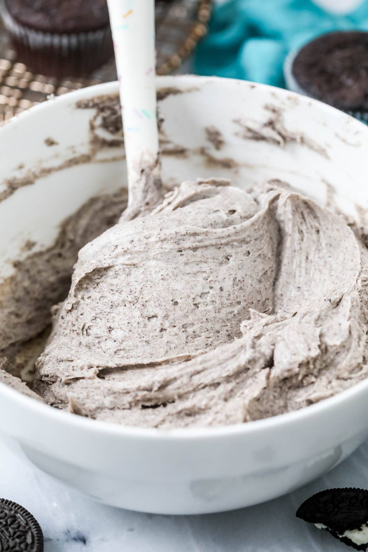 Cookies and cream frosting in a bowl with a spatula stirring it.