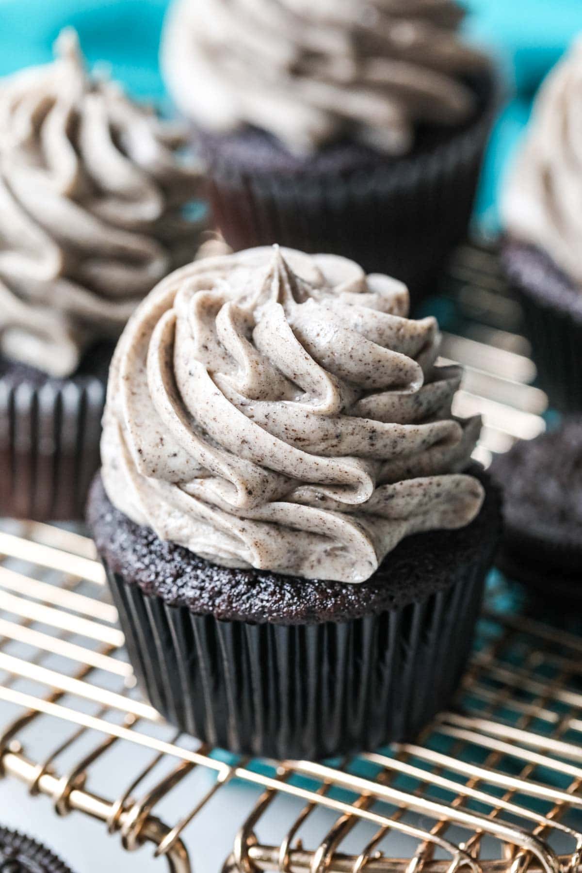 Close shot of a dark chocolate cupcake topped with piped Oreo frosting.
