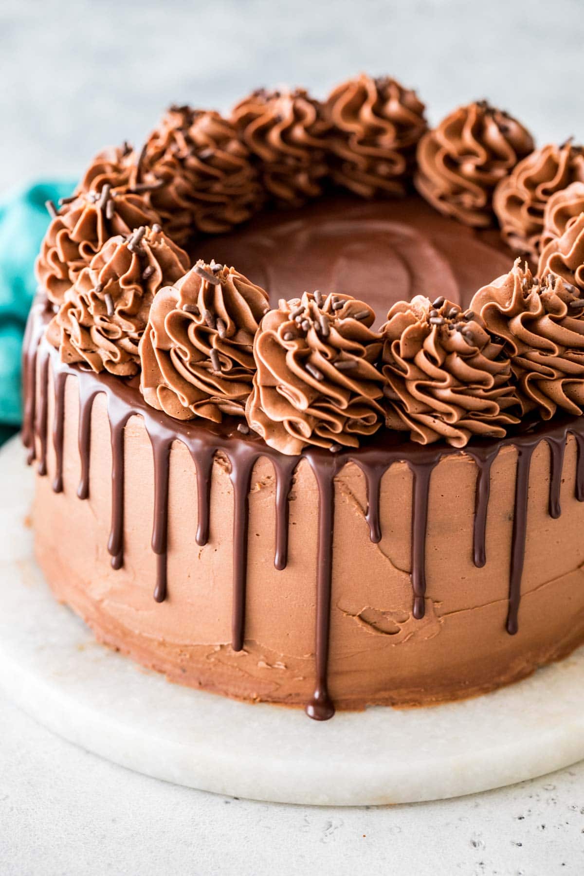 Chocolate cake topped with ganache drips and chocolate icing swirls.