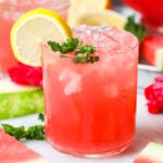 Glass of watermelon lemonade garnished with fresh mint and lemon slices.