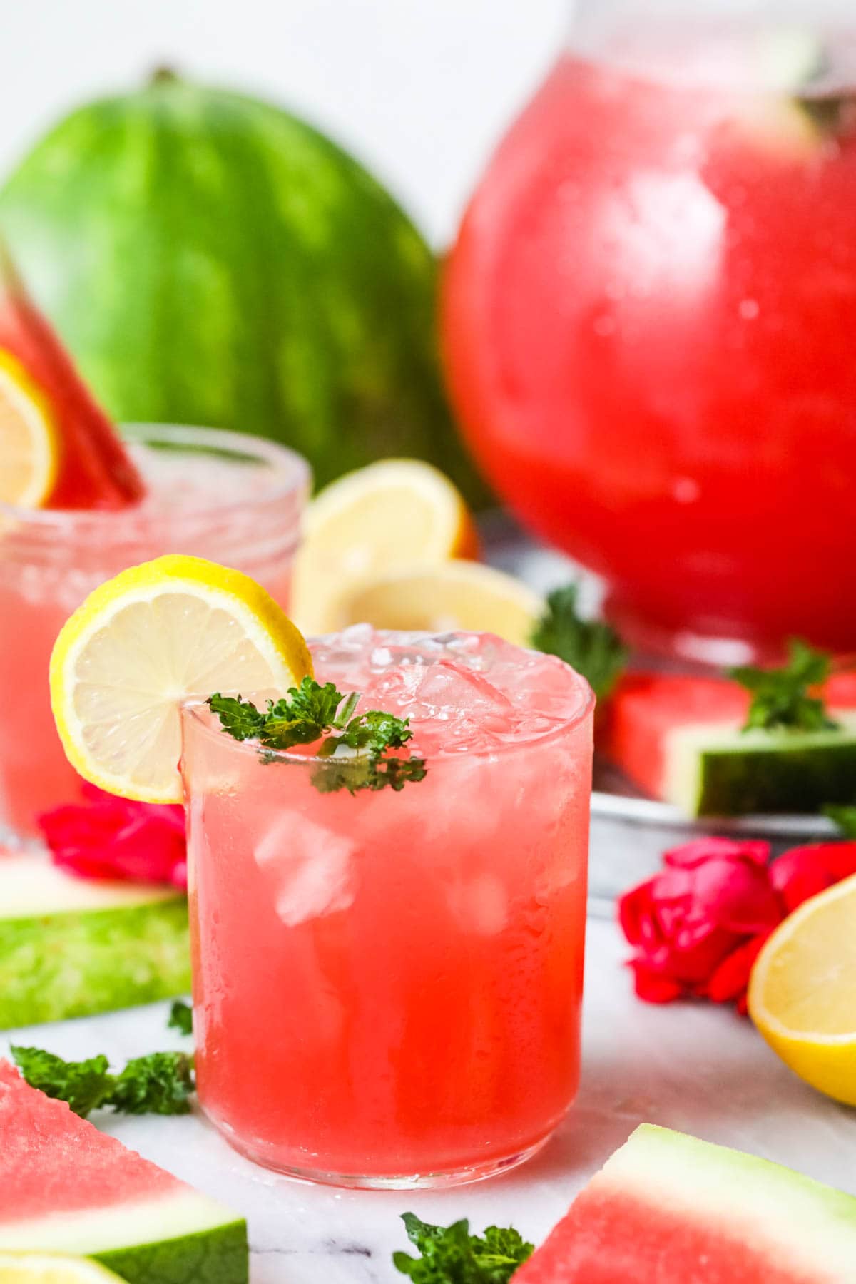 Glass of watermelon lemonade garnished with fresh mint and lemon slices.