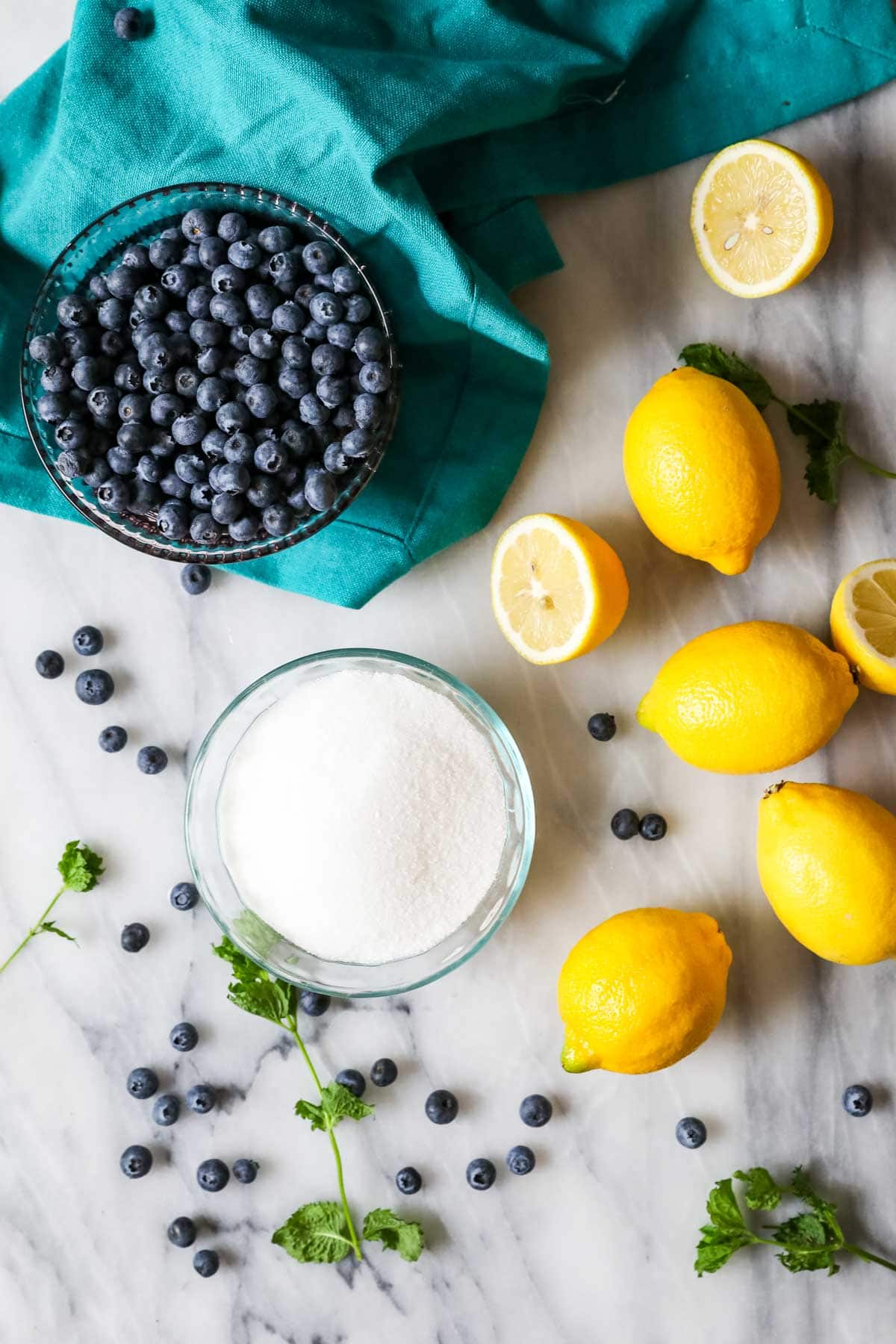 Overhead view of ingredients including blueberries, sugar, and lemons.