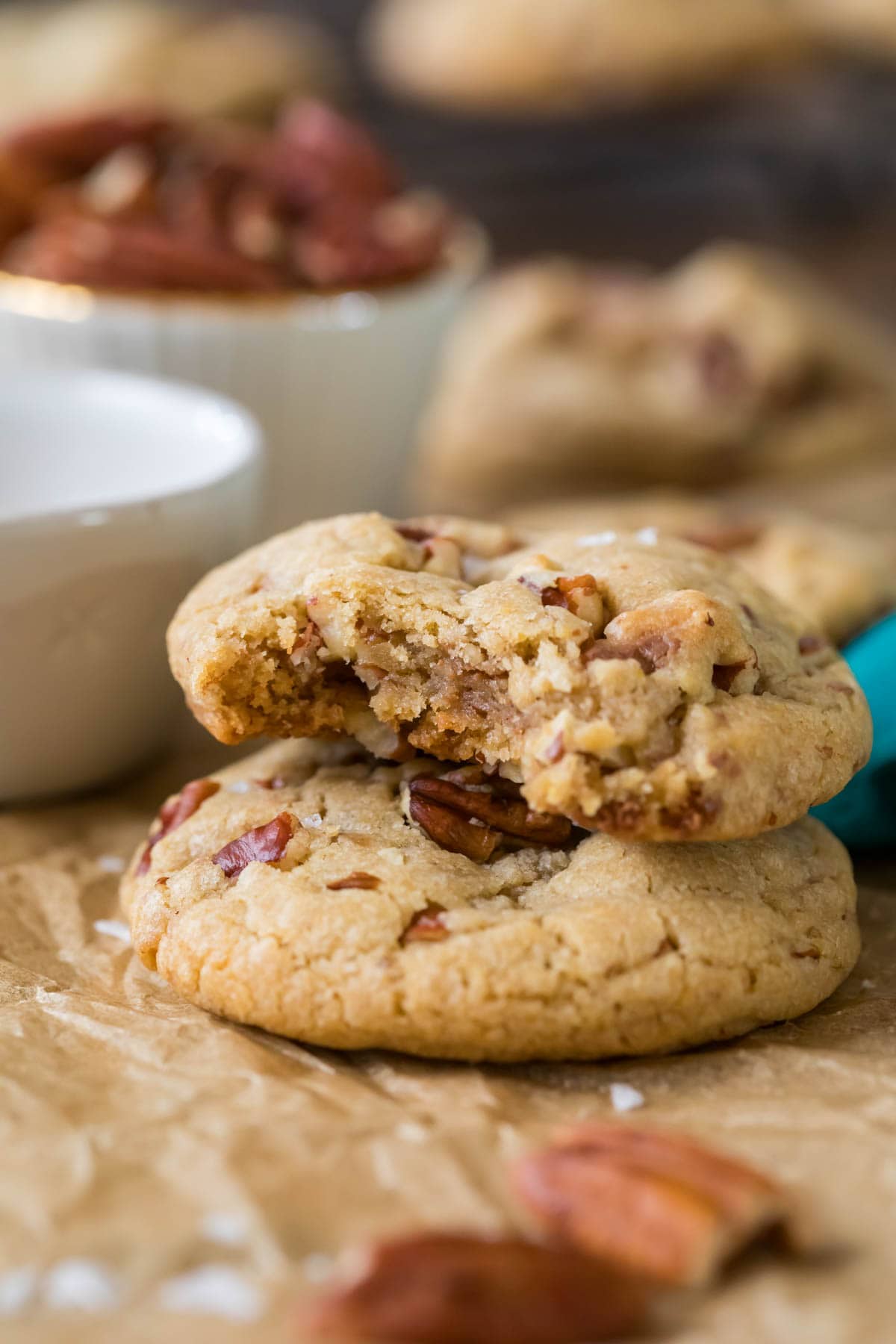 Two butter pecan cookies stacked on top of each other with the top cookie missing a bite.