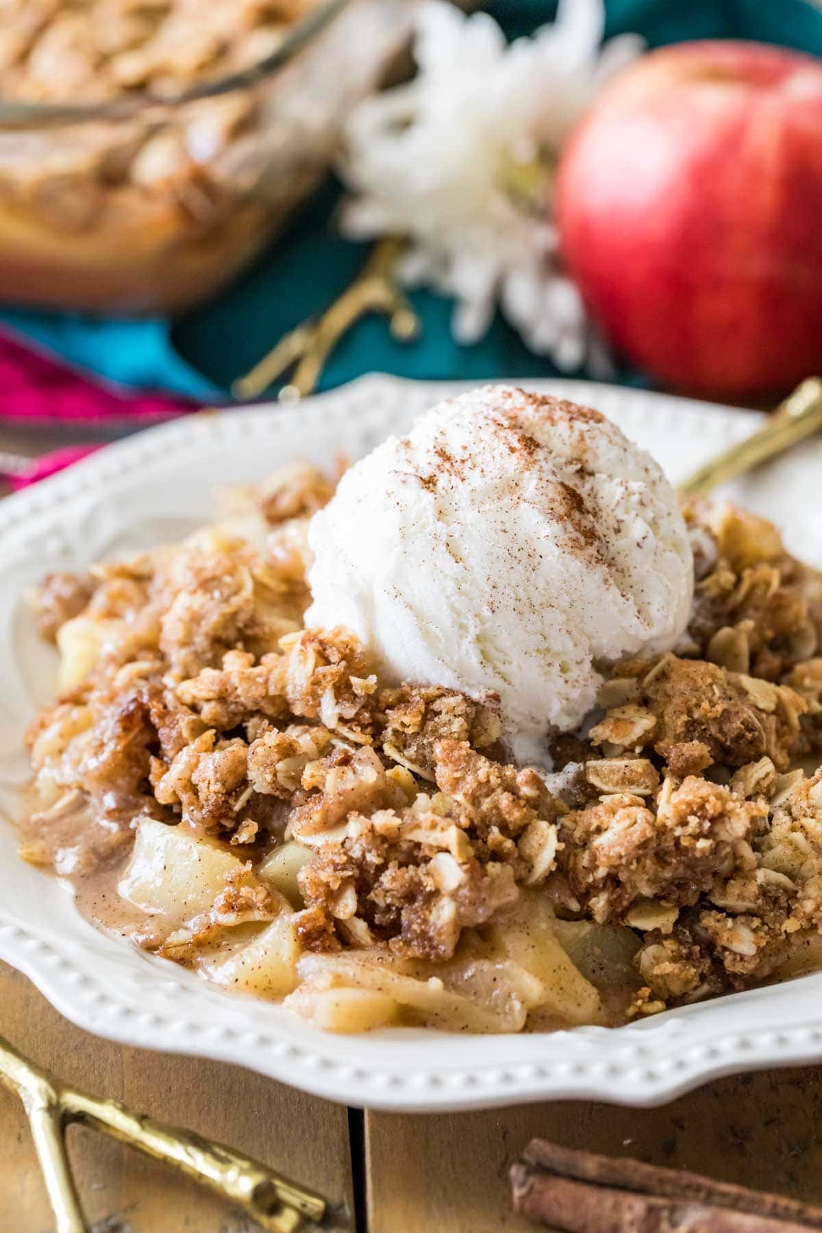 Bowl of apple crisp topped with a scoop of vanilla ice cream and cinnamon.