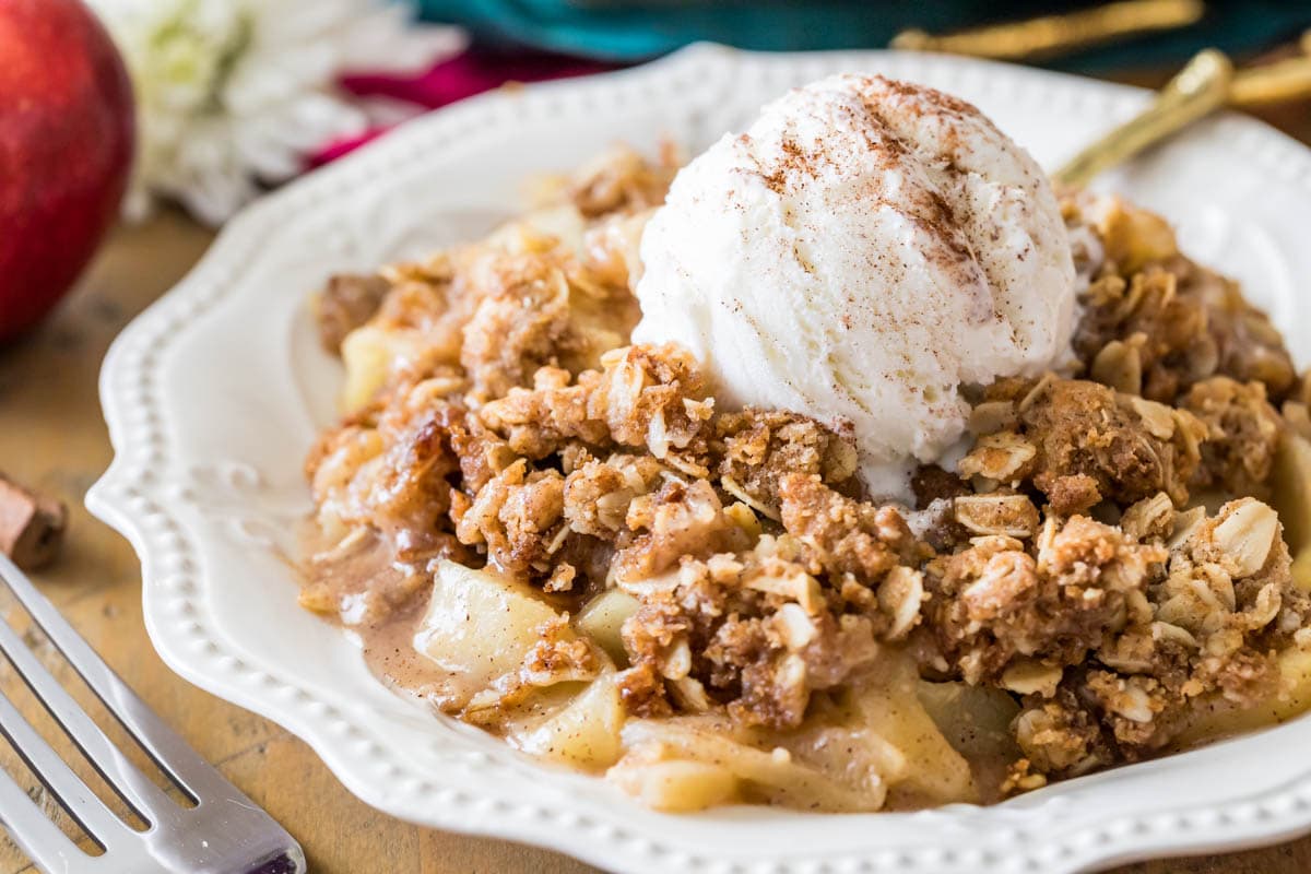 Bowl of apple crisp topped with a scoop of vanilla ice cream and cinnamon.