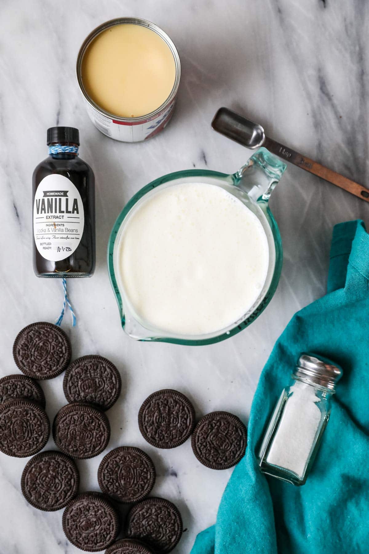 Overhead view of ingredients including condensed milk, heavy cream, Oreo cookies, vanilla, and salt.