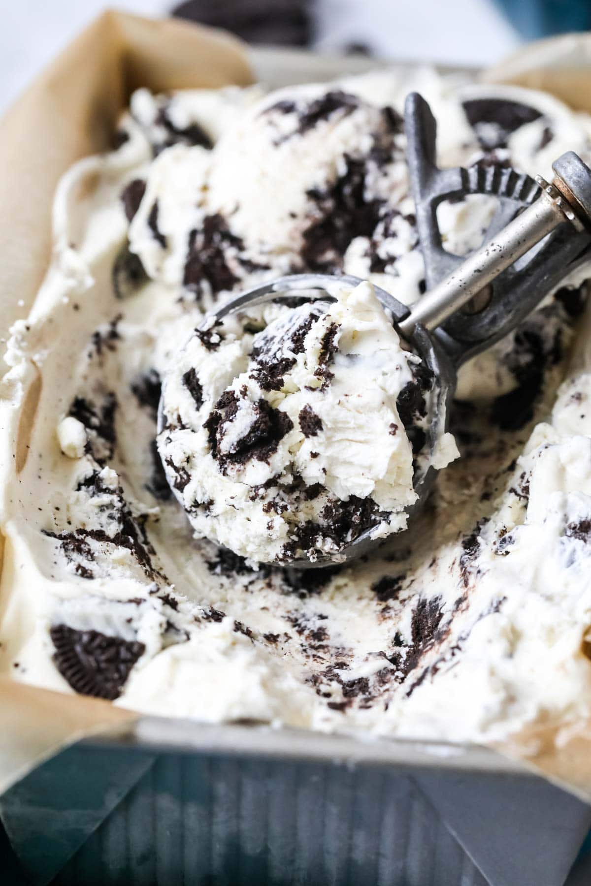 Close-up view of an ice cream scoop scooping Oreo ice cream from a pan.