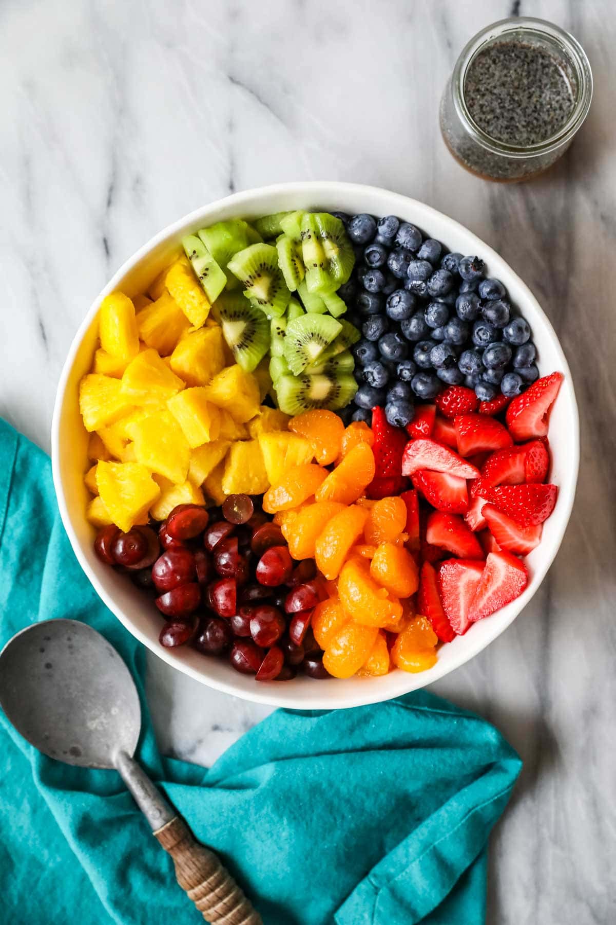 Overhead view of a bowl of different fruits organized into sections.