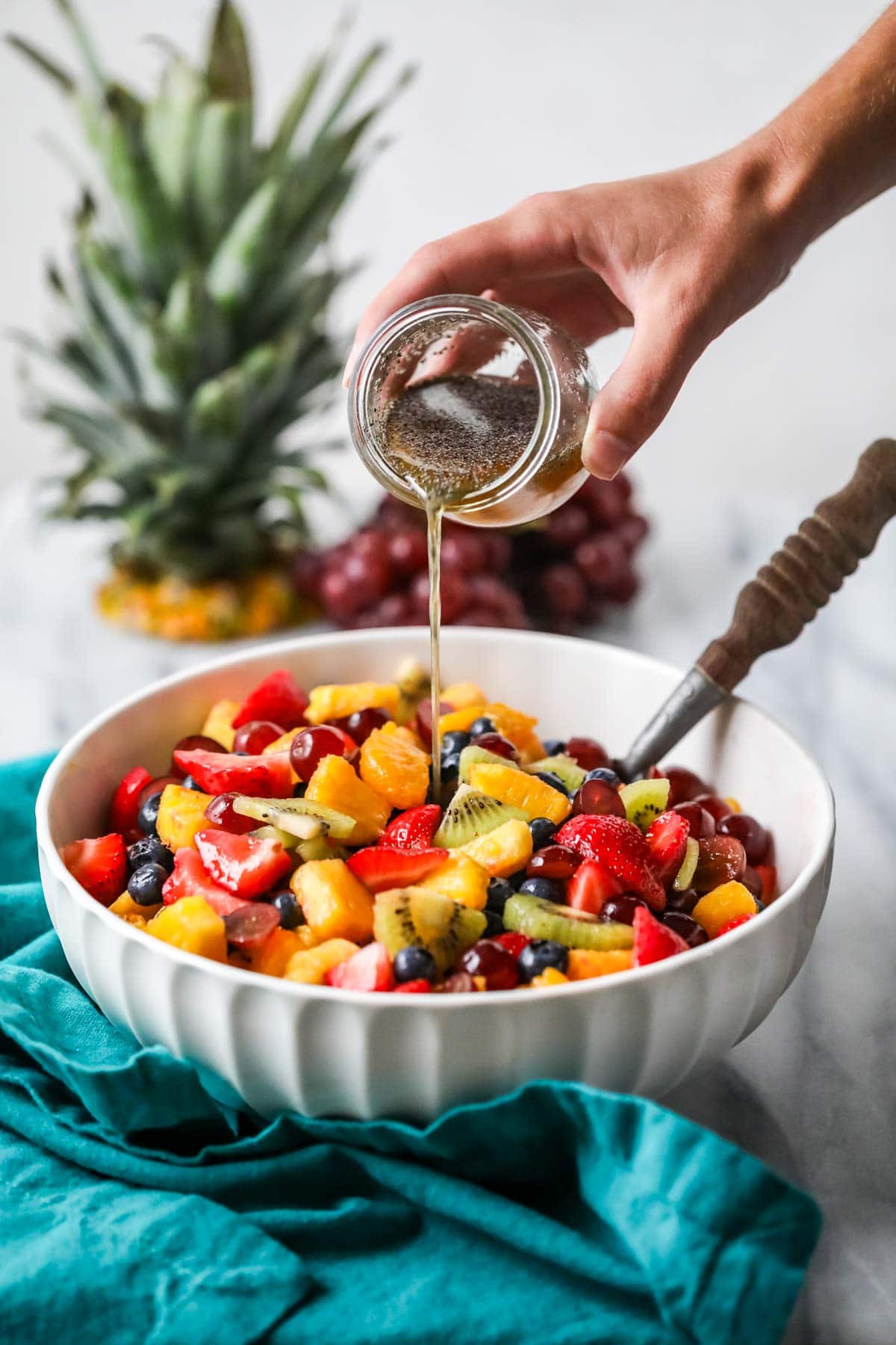 Dressing being poured over fruit salad.