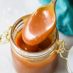 Caramel sauce being spooned out of a jar.