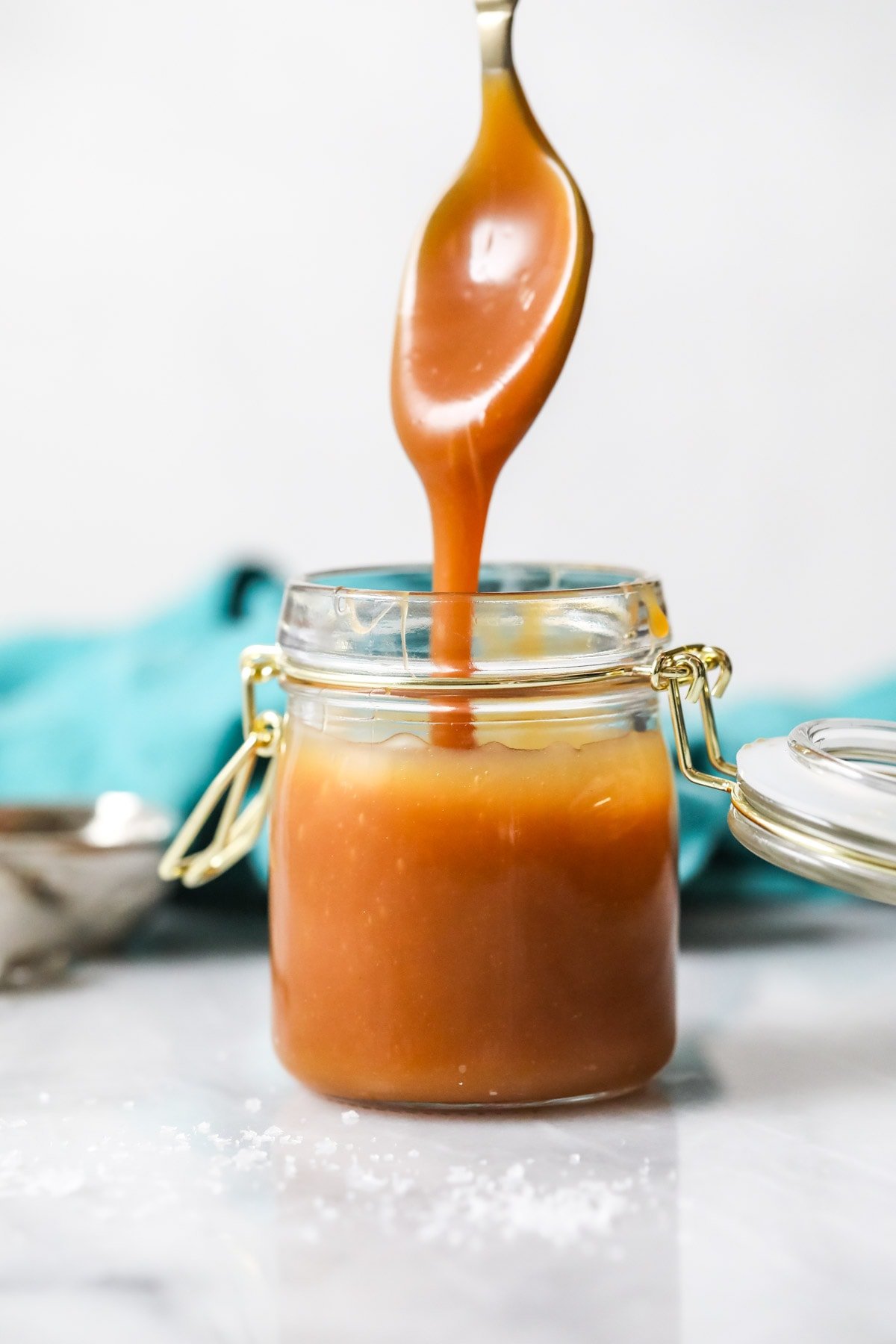 Caramel sauce dripping off a spoon into a jar.