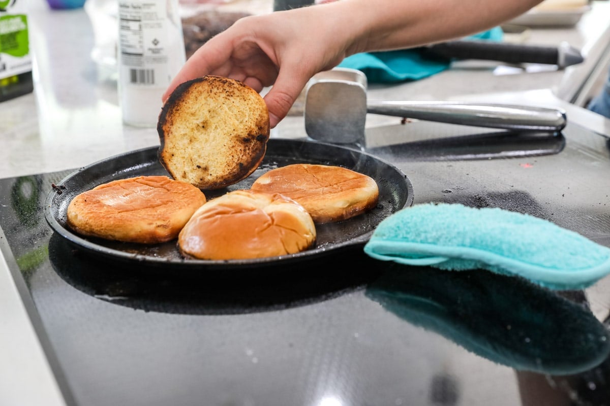 Buns being toasted on a hot griddle.