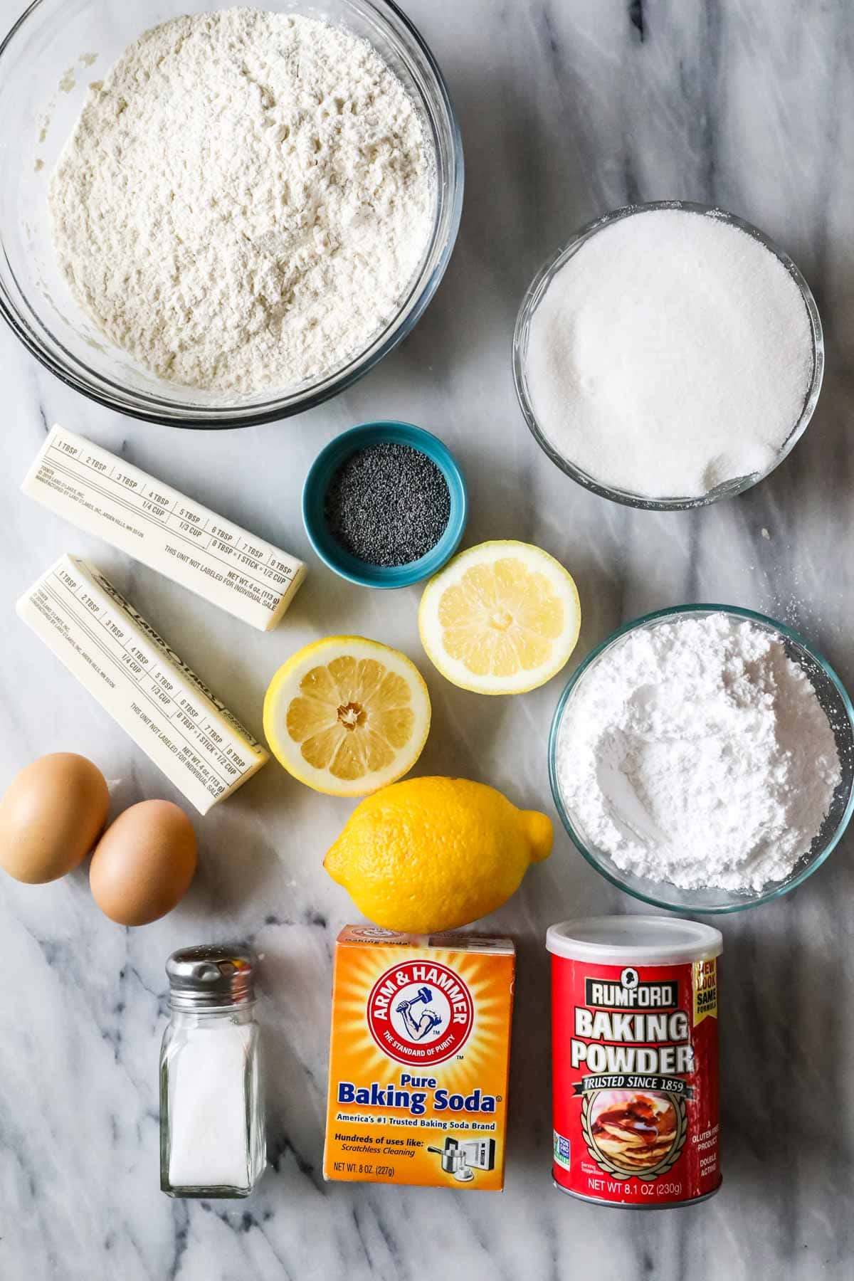Overhead view of ingredients including flour, butter, lemons, poppy seeds, and more.