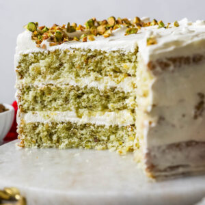 Cross section of a pistachio cake made with three layers of green cake and a swiss meringue buttercream frosting.