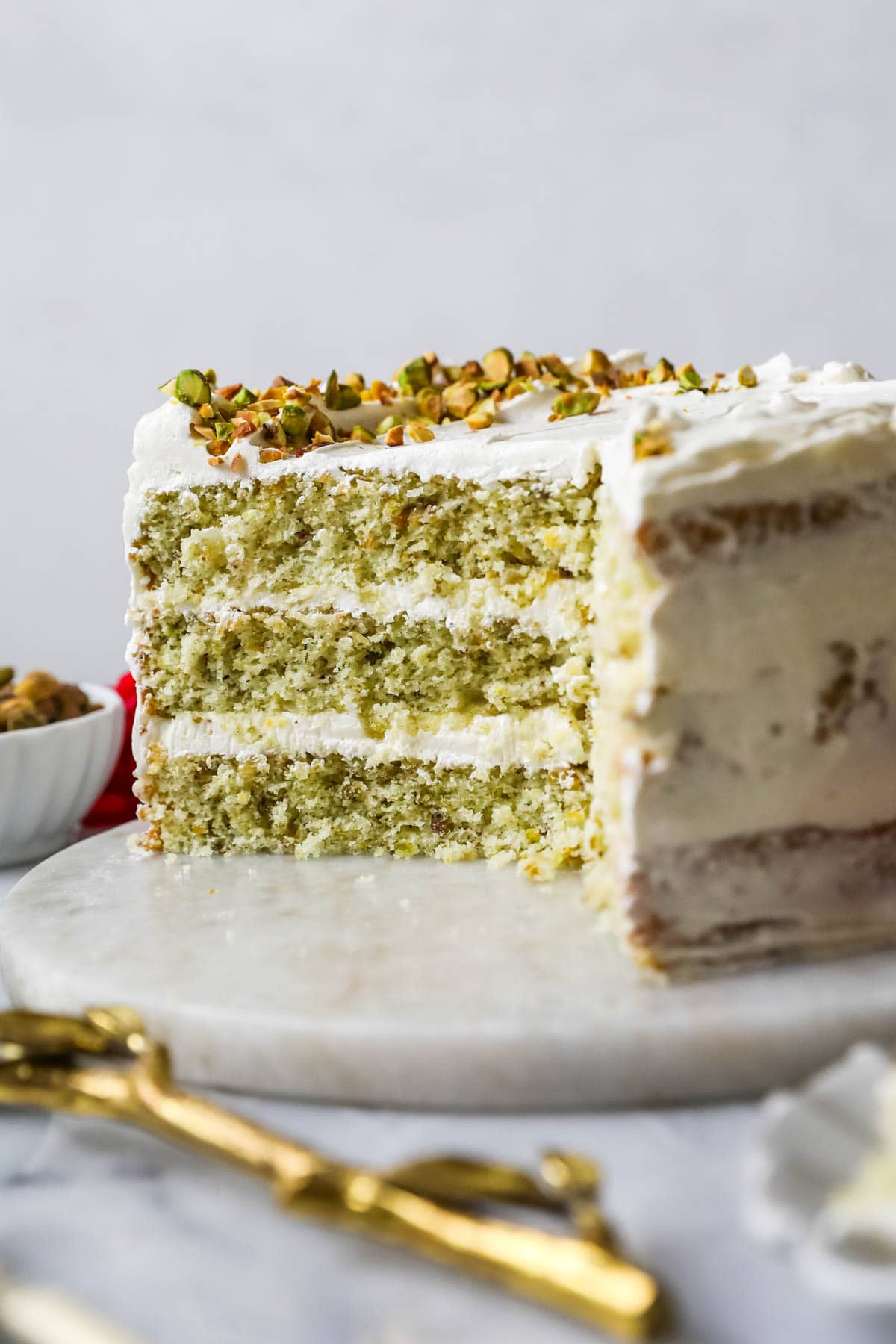 Cross section of a pistachio cake made with three layers of green cake and a swiss meringue buttercream frosting.
